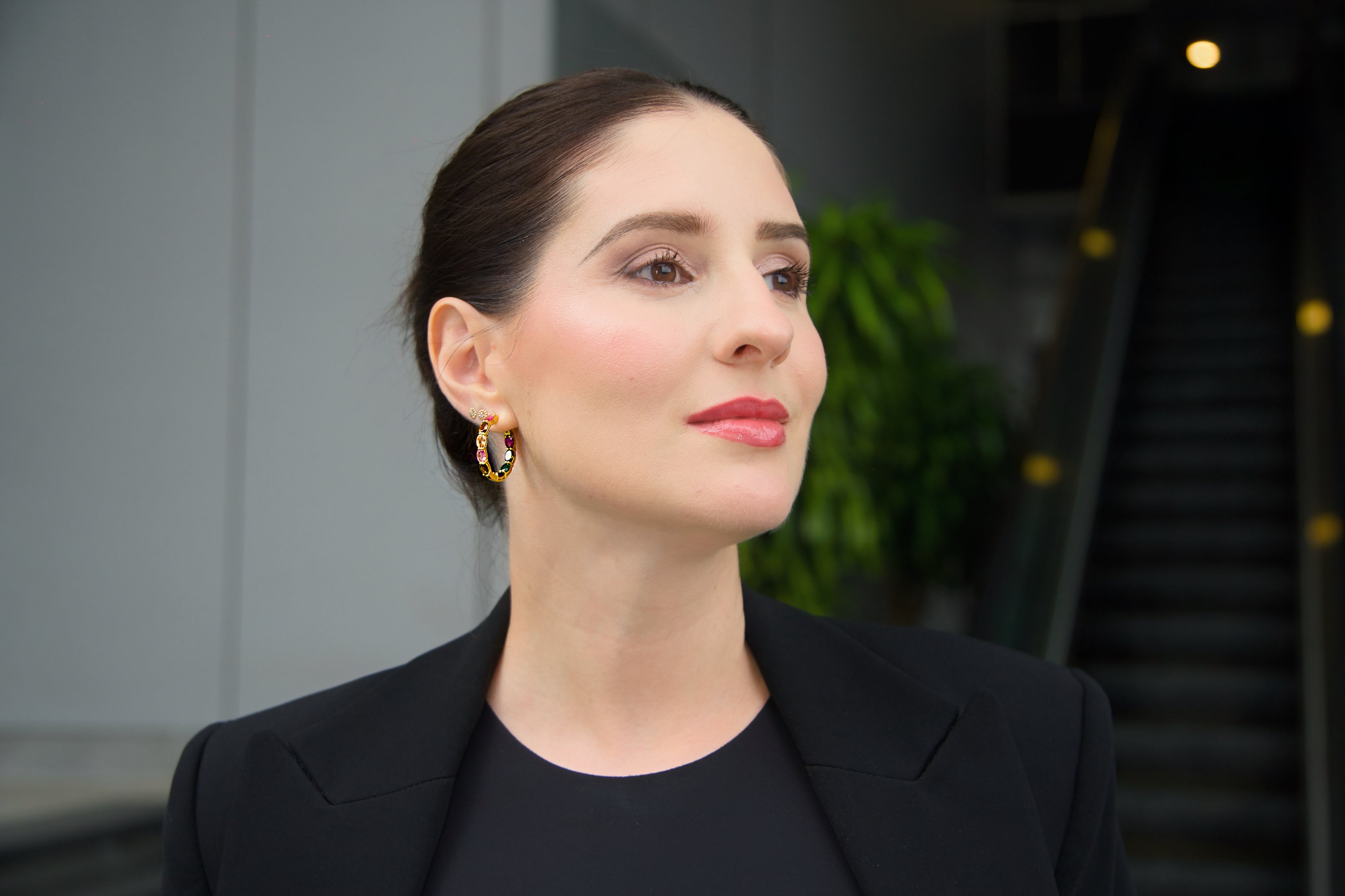 Woman wearing a black blazer and earrings with a blurred background