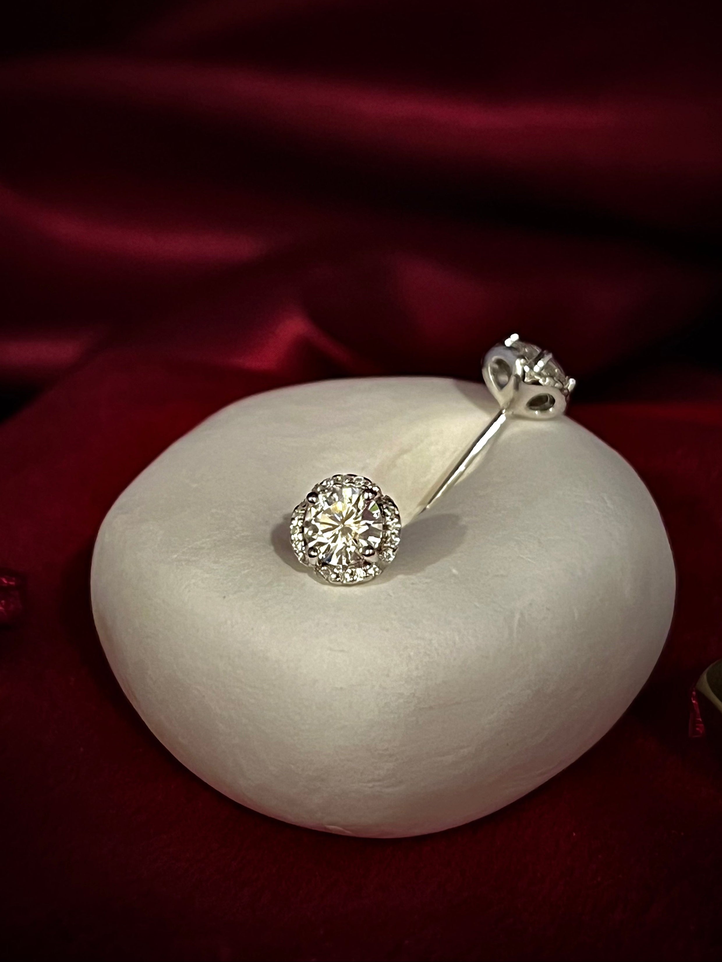 Silver earrings with gemstones on a white stone against a red fabric background