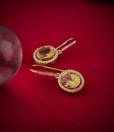 Haspiera citrine yellow hook earrings with oval gemstone and surrounding smaller stones on red background