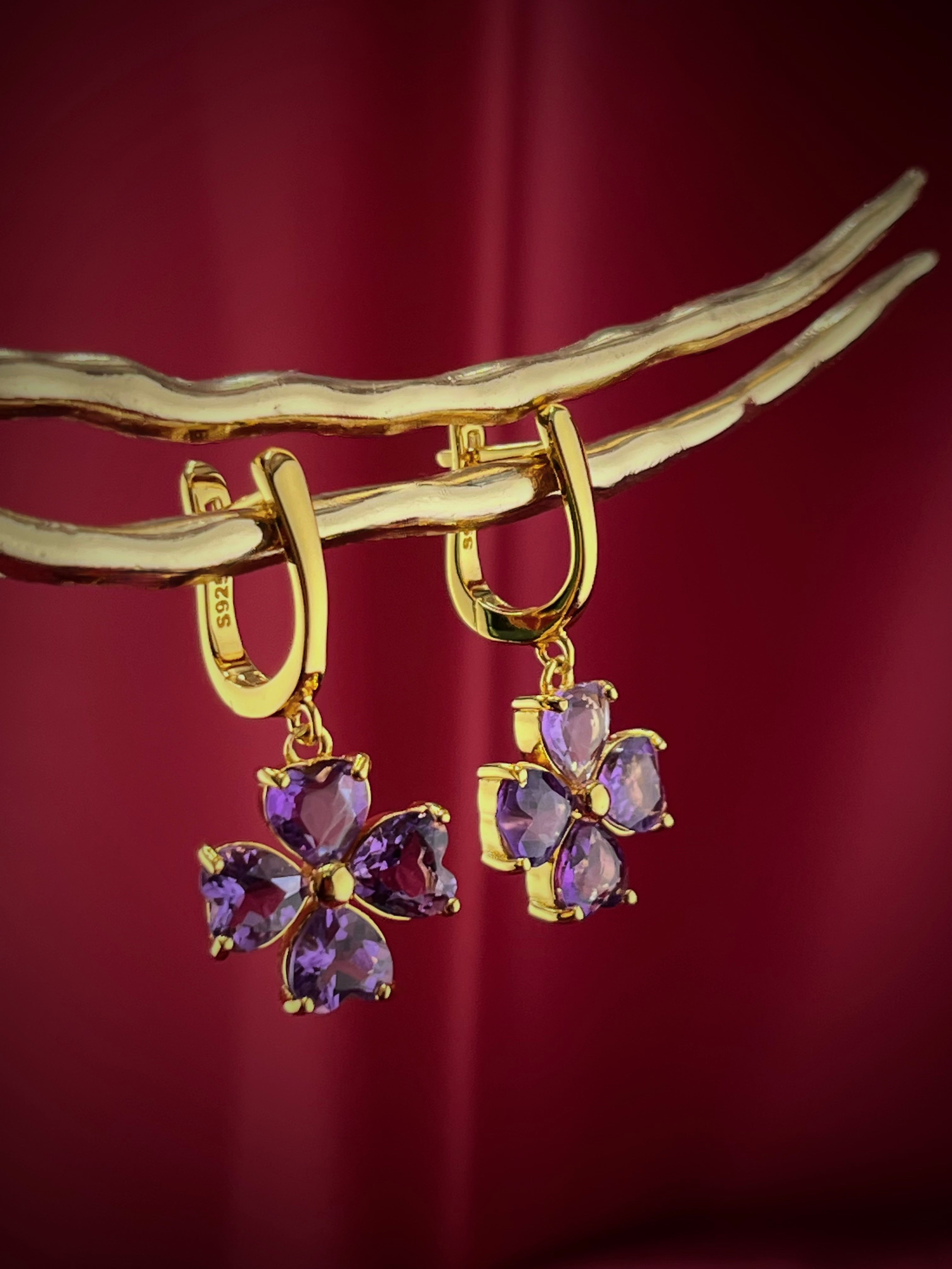 Haspiera four petal amethyst earrings with gold settings hanging on golden branches