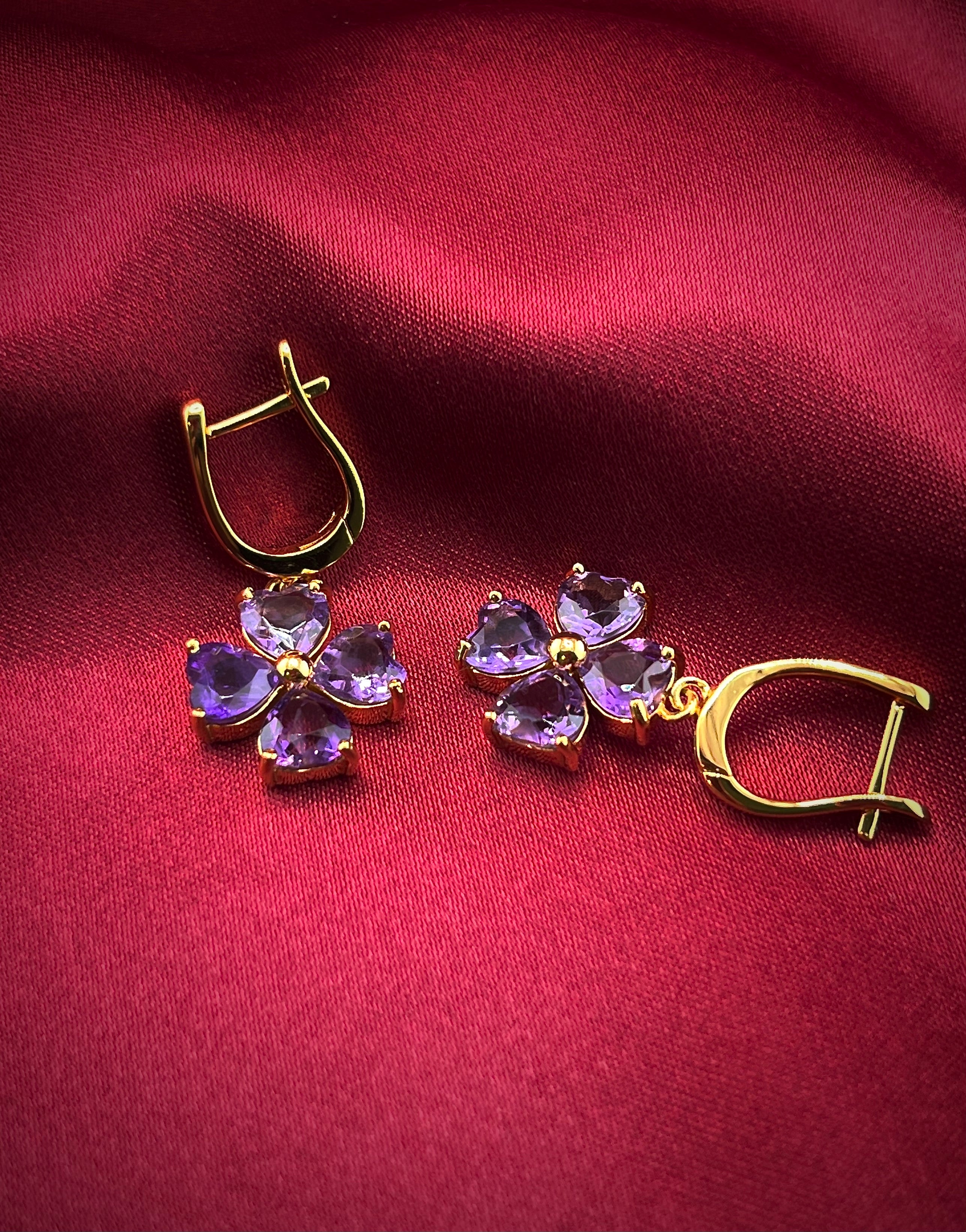 Haspiera four petal amethyst earrings with gold setting displayed on red fabric background