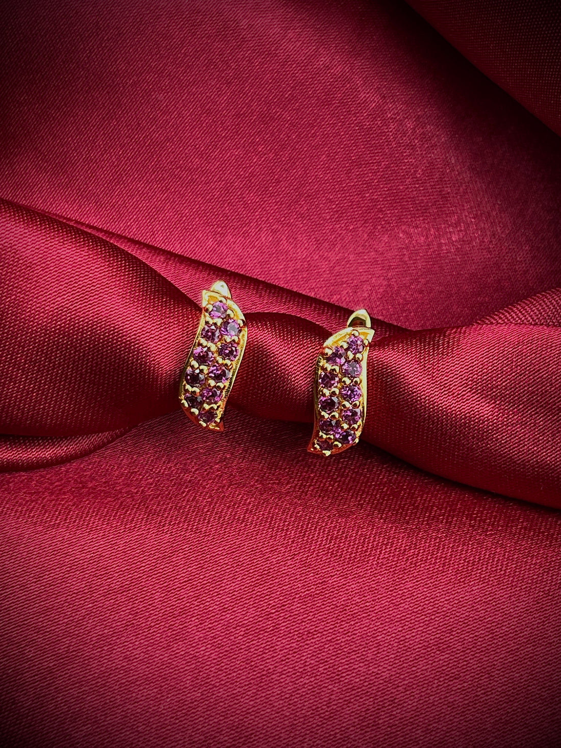 Haspiera berry leaf purple earrings with gold setting on red satin fabric background
