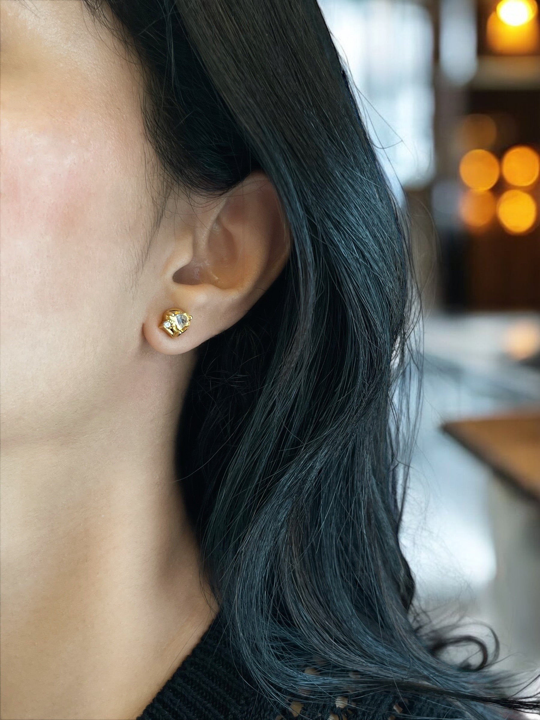 Haspiera golden heart stud earrings worn by woman with dark hair in a softly lit indoor setting