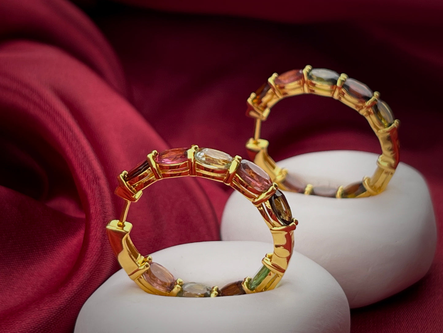 Haspiera multicolor gemstone hoop earrings with gold setting displayed on white cushions