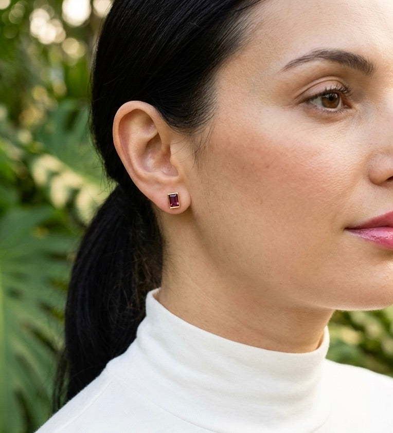 Woman wearing a white turtleneck with a blurred green leafy background