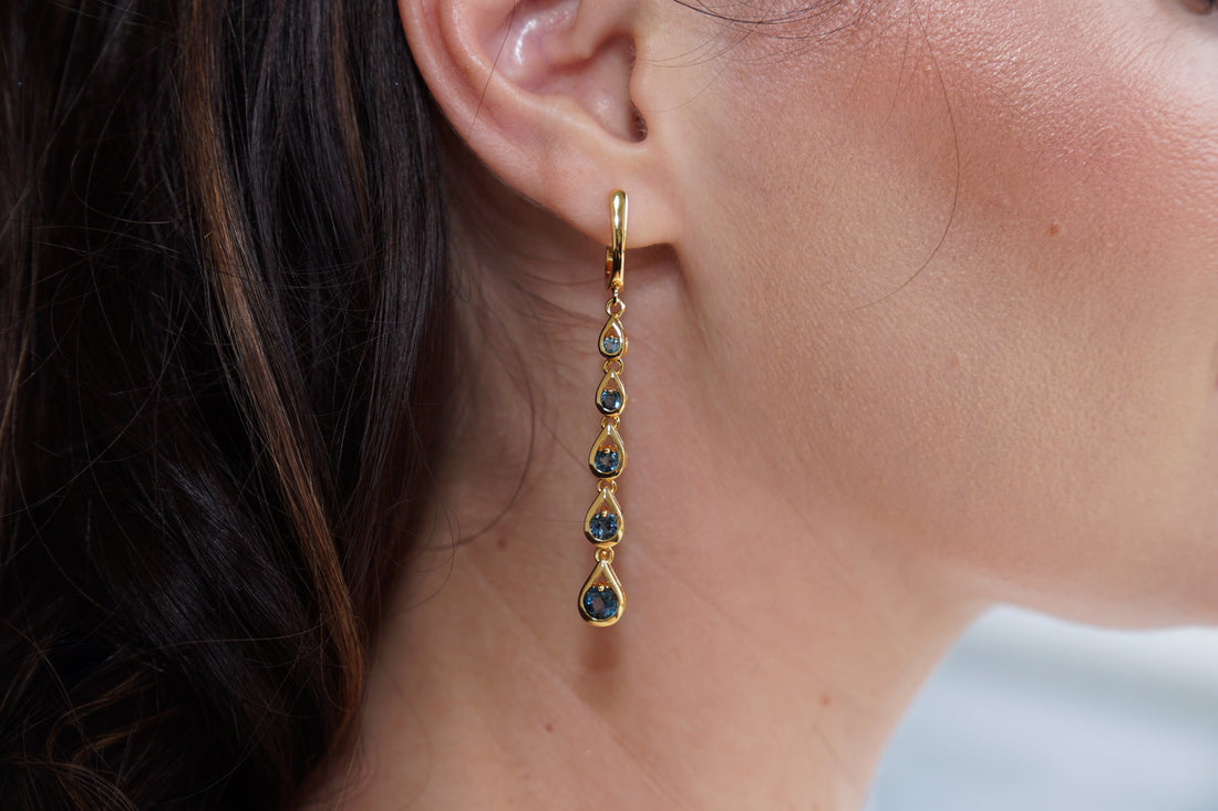 Gold earring with green gemstones worn by a person