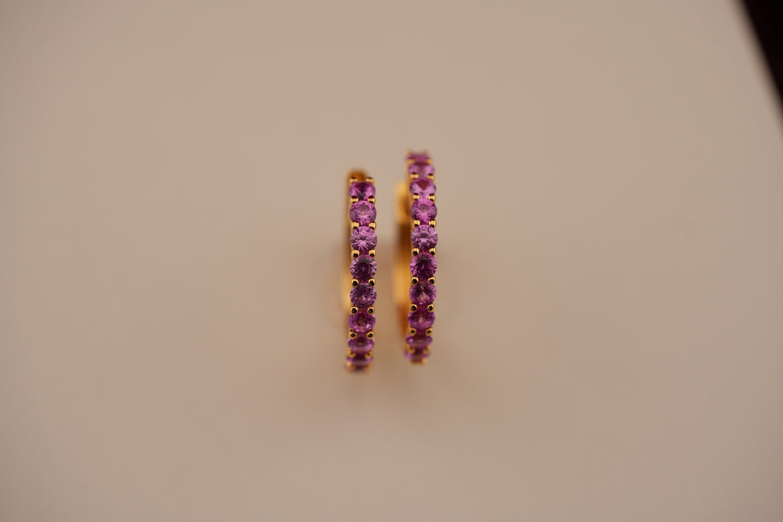 Pair of purple hoop earrings on a beige background