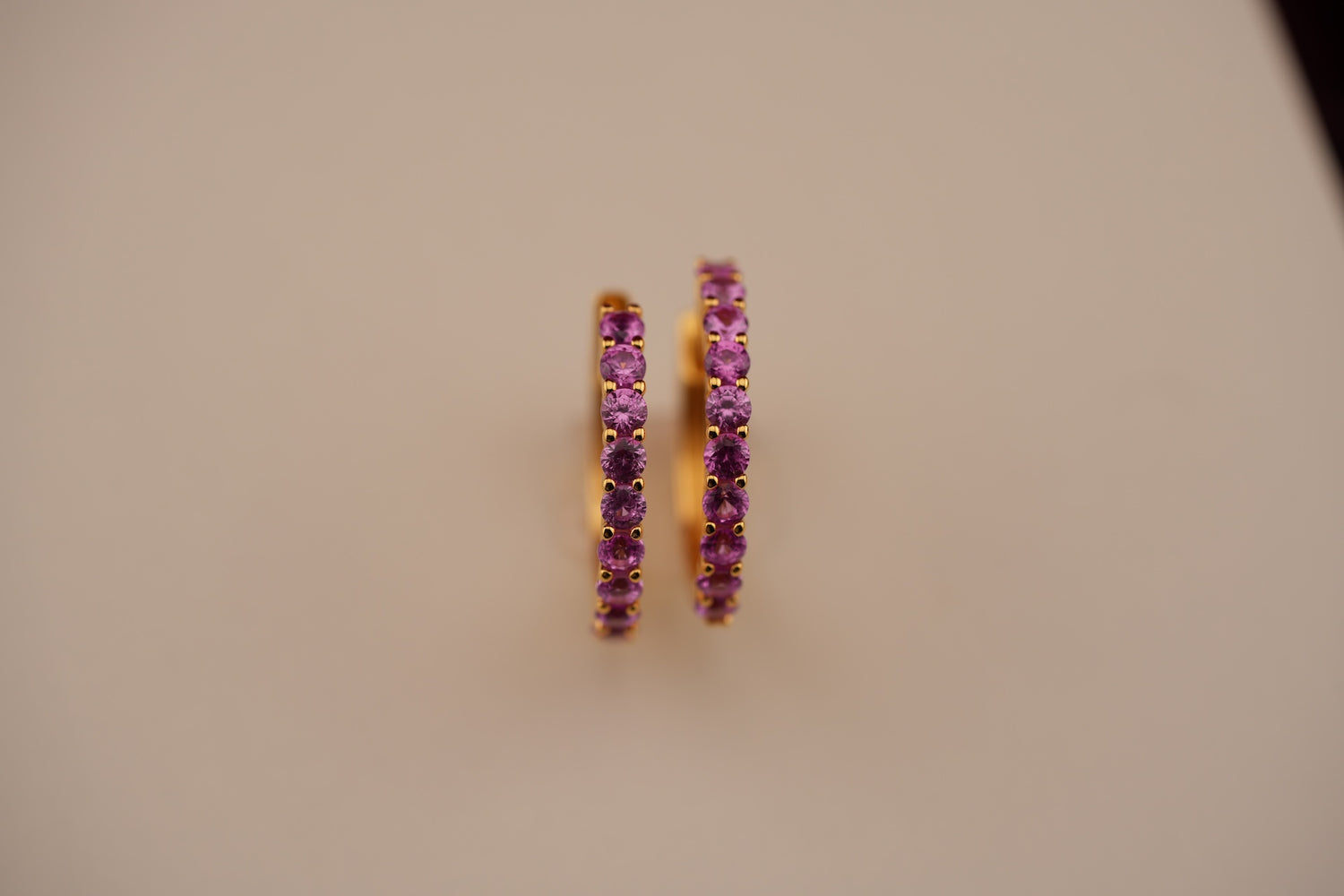 Pair of purple hoop earrings on a beige background