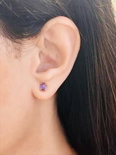 Haspiera amethyst stud earrings worn on ear with purple gemstone in gold setting