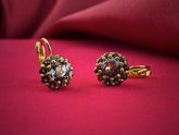 Haspiera celestial blue flower earrings with gemstone petals set in gold on red background