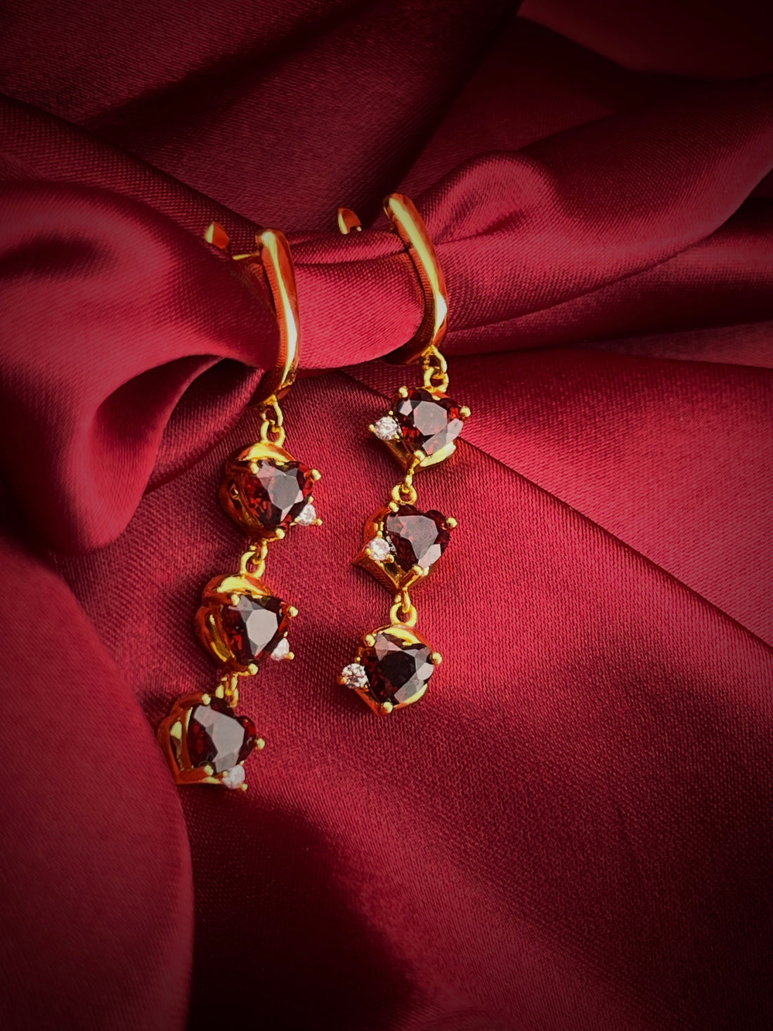 Haspiera demi-fine gemstone earrings for women with red stones and gold setting on red fabric