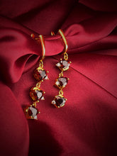 Haspiera demi-fine gemstone earrings for women with red stones and gold setting on red fabric