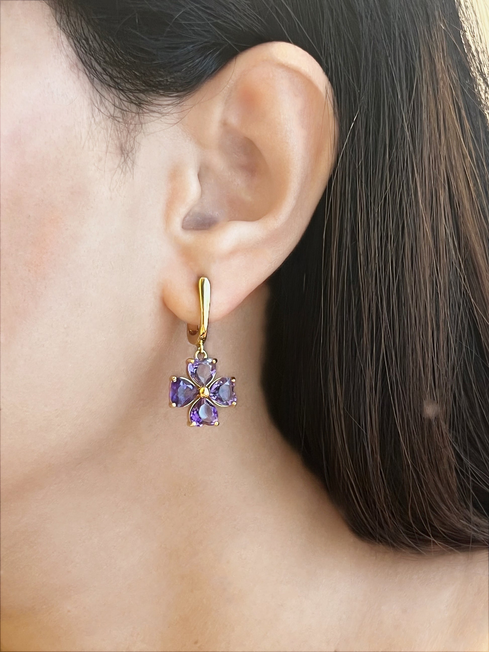 Haspiera four petal amethyst earrings with gold setting worn on ear for gemstone jewelry