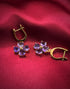 Haspiera four petal amethyst earrings with gold setting displayed on red fabric background
