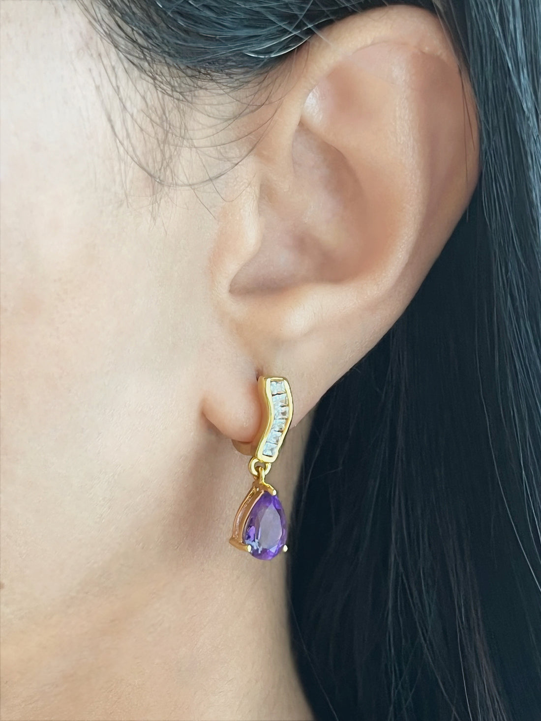 Haspiera petite purple drop earrings with gold setting and clear gemstones worn on ear