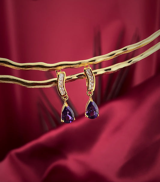 Haspiera petite purple drop earrings with gold setting and small clear stones on a burgundy background