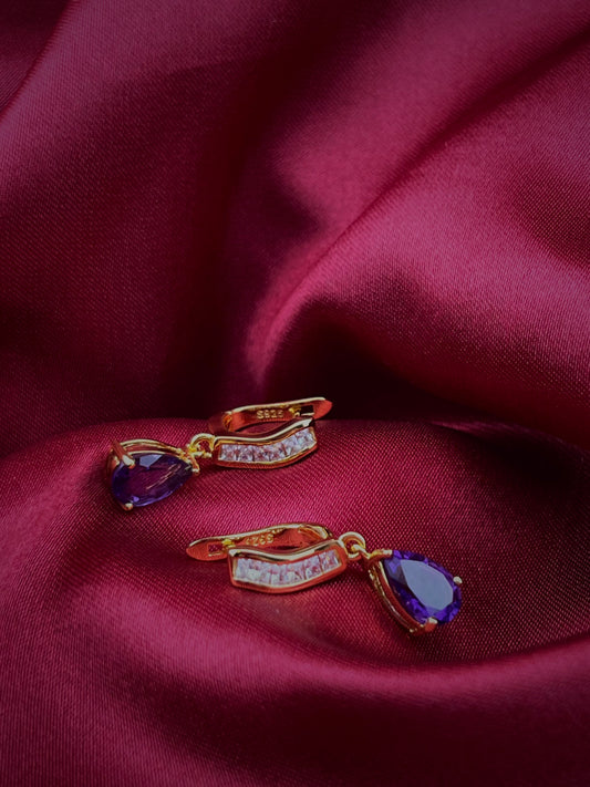 Haspiera petite purple drop earrings with gold setting and gemstone accents on purple fabric