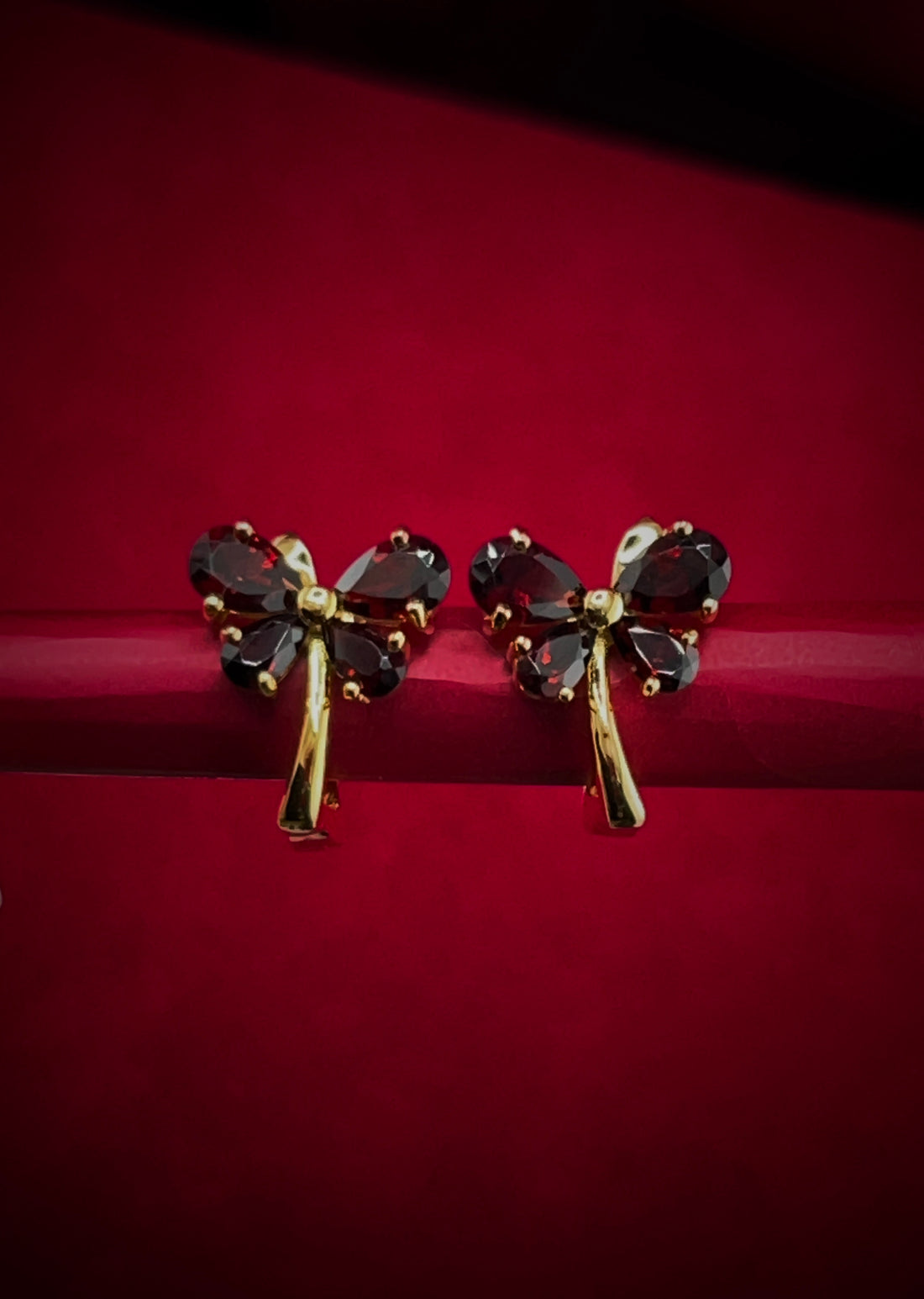 Haspiera red butterfly earrings with gemstone petals and gold-tone stems on red background
