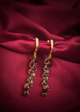 Haspiera red garnet dangle earrings with gold settings displayed on red silk fabric