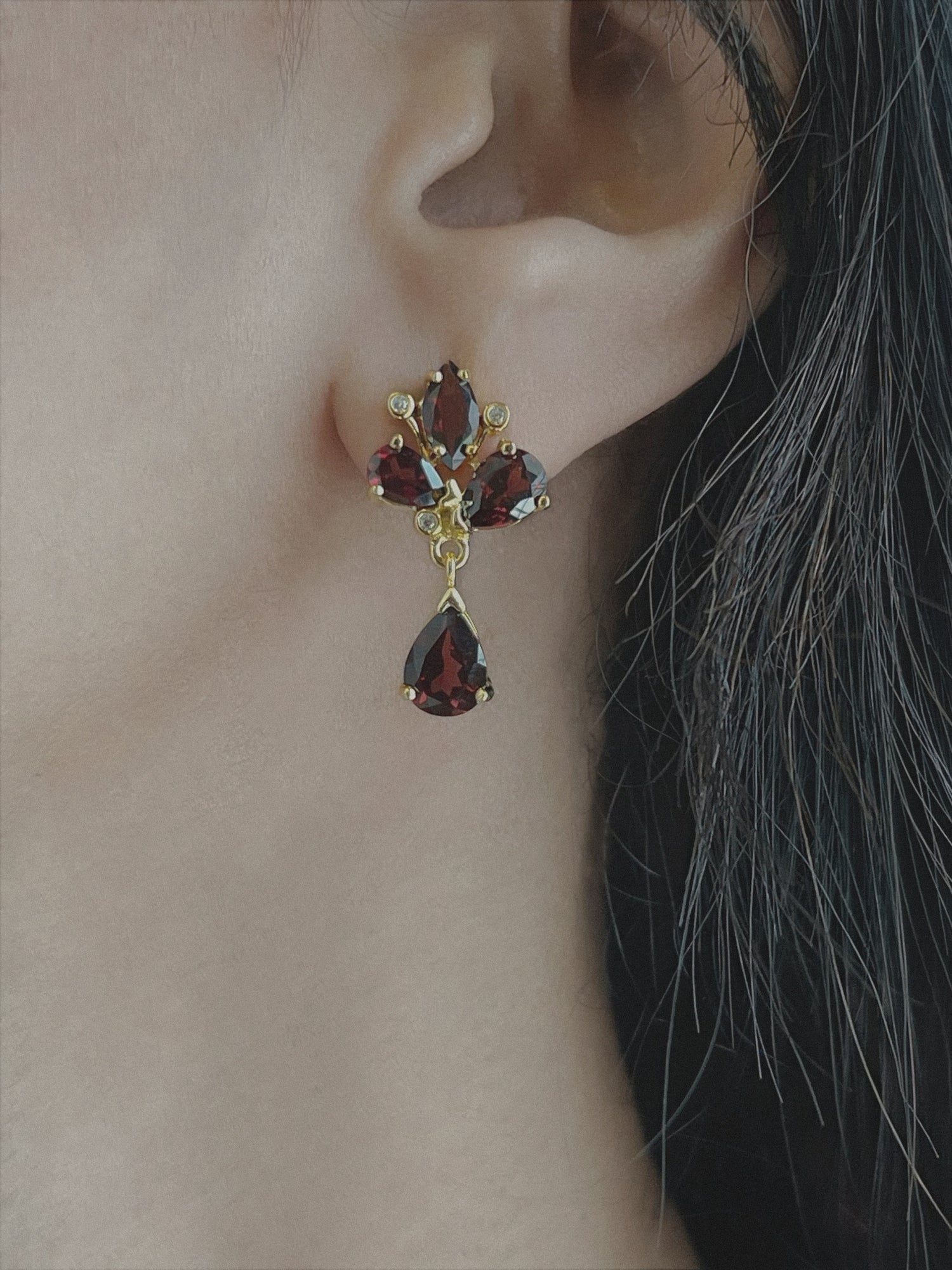 Haspiera red trillium drop earrings featuring deep red gemstones set in gold on a woman&