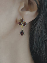 Haspiera red trillium drop earrings featuring deep red gemstones set in gold on a woman&