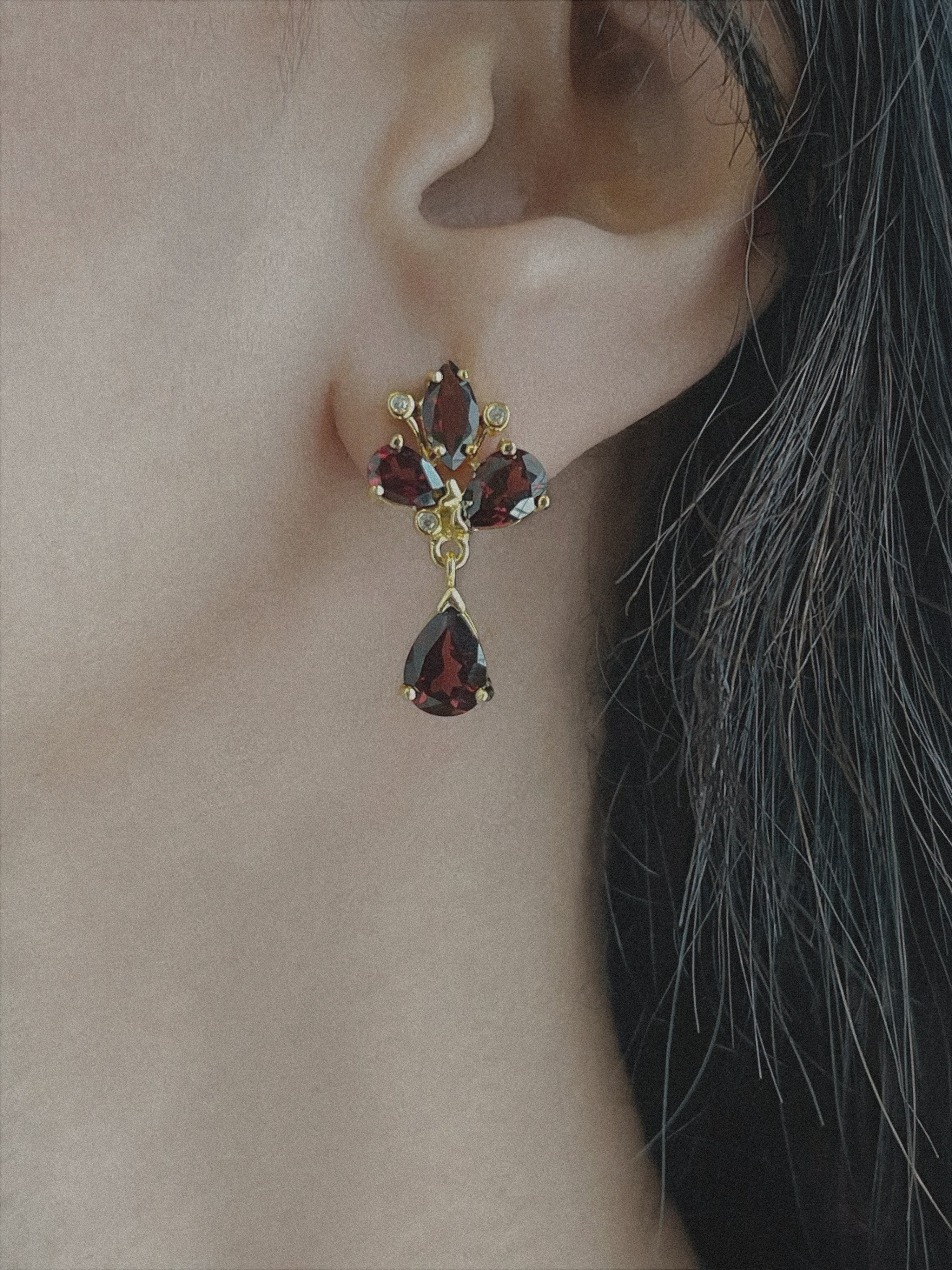 Haspiera red trillium drop earrings featuring deep red gemstones set in gold on a woman&