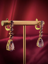 Haspiera royal lilac dangle earrings with purple gemstones and gold setting on display stand