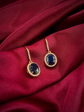 Haspiera sapphire drop earrings for women with gold setting and oval blue gemstones on red fabric