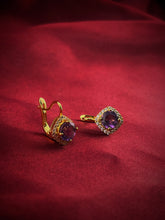 Haspiera violet amethyst halo gemstone earrings with gold setting on red fabric background